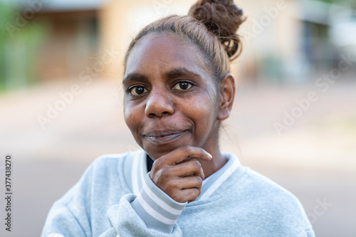 head and shoulders of young aboriginal woman looking at camera with hand to chin photo