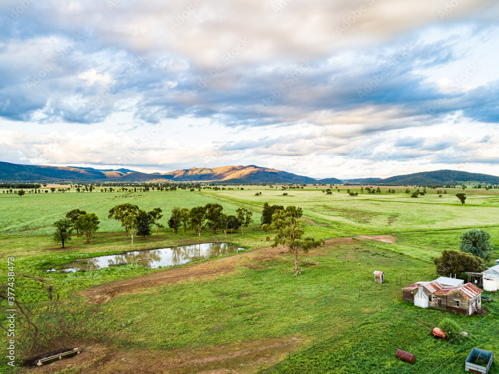 Last sunlight on hills past green farm paddocks and dam Last sunlight on hills past green farm paddocks and dam