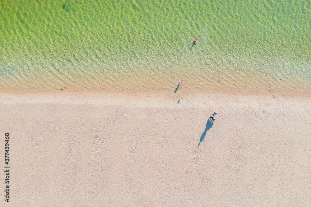 Aerial view beachgoers casting long shadows on a sandy beach Aerial view beachgoers casting long shadows on a sandy beach