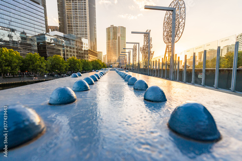 Looking along the steel girders and metal sculptures of the Sandridge Bridge in Melbourne at sunset. photo