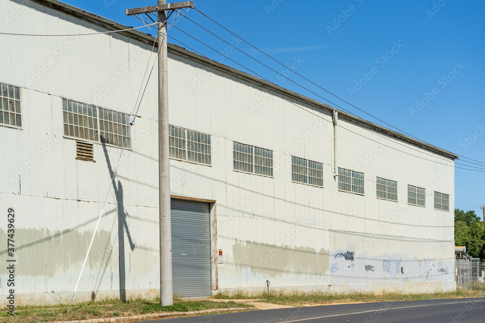 A power pole outside the door of a large corrugated iron warehouse A power pole outside the door of a large corrugated iron warehouse