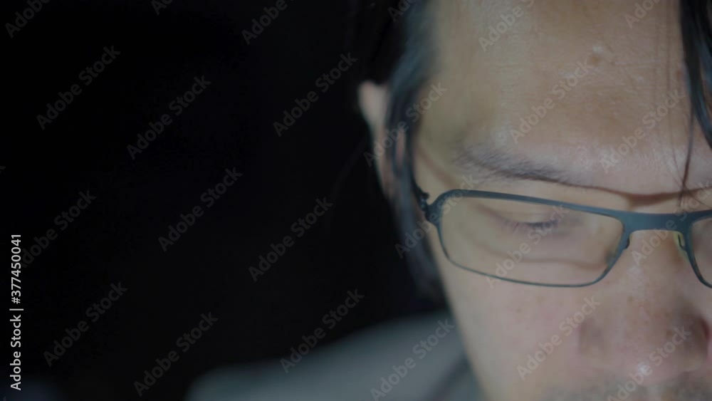 4K Video close up face of 30 year old asian man with light from mobile phone with black background. Concept for cellphone technology and touchscreen 4K Video close up face of 30 year old asian man with light from mobile phone with black background. Concept for cellphone technology and touchscreen