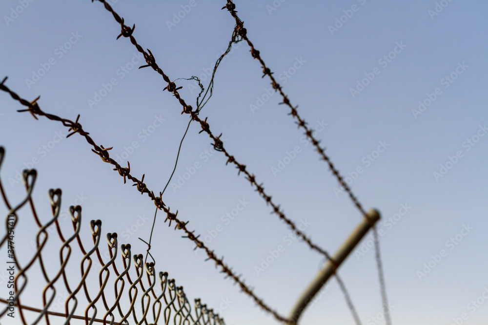 a barbed wire fence against a blue sky a barbed wire fence against a blue sky