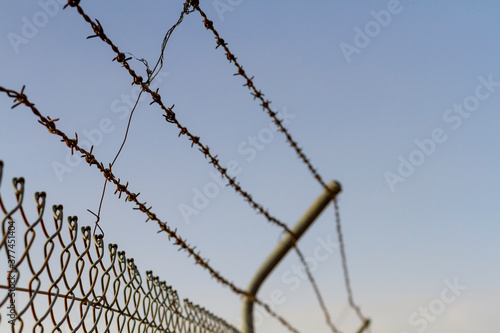 A barbed wire fence against a blue sky