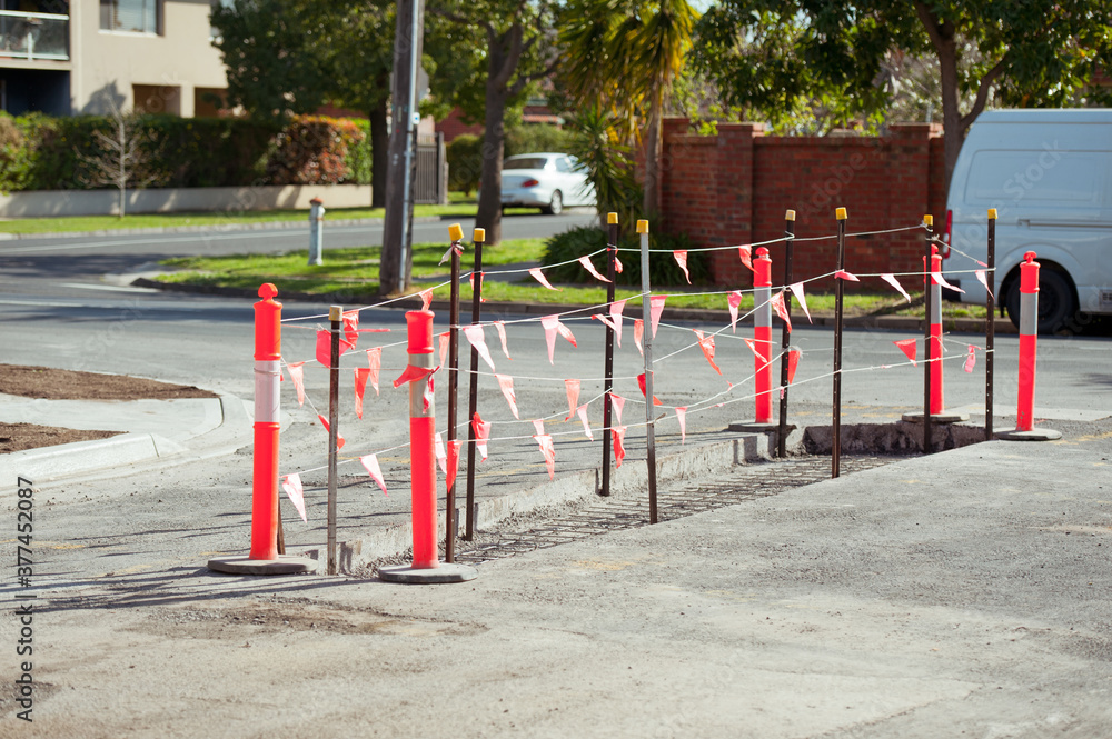 Road works. Construction side. Road repair. The hole in the asphalt is closed by a protective fence with red flags.