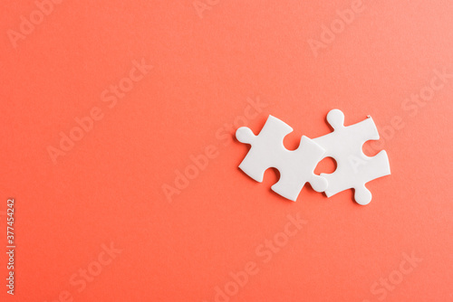 Fototapeta Naklejka Na Ścianę i Meble -  Top view flat lay of two paper plain white jigsaw puzzle game last pieces for solve, studio shot on a red background, quiz calculation concept