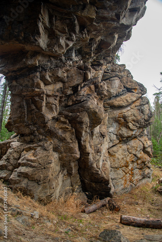 
Stone mountains. 
Stone texture. Mountain gorge. Among the huge rocky mountains there is a mountain river, the mountains are covered with fresh bright green foliage of trees in early spring.
