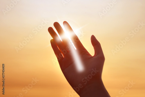 Cross of light on human hand concept of religion