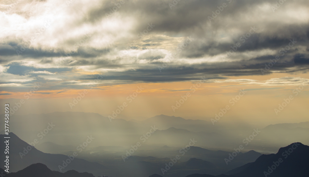 beautiful landscape of hills and mountains silhouette during sunrise. light breaking through cloud cover. mist covered mountains and hills 