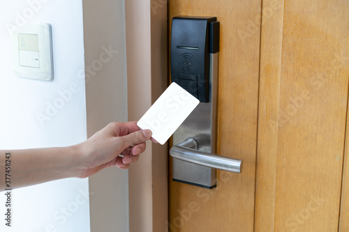 Door access control - woman hand holding white mockup key card to lock and unlock door. digital door lock. photo