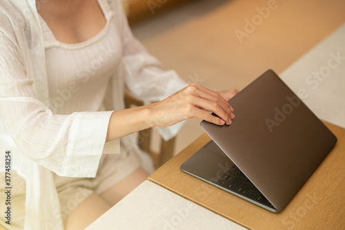 Woman hand open or close laptop on wood table.