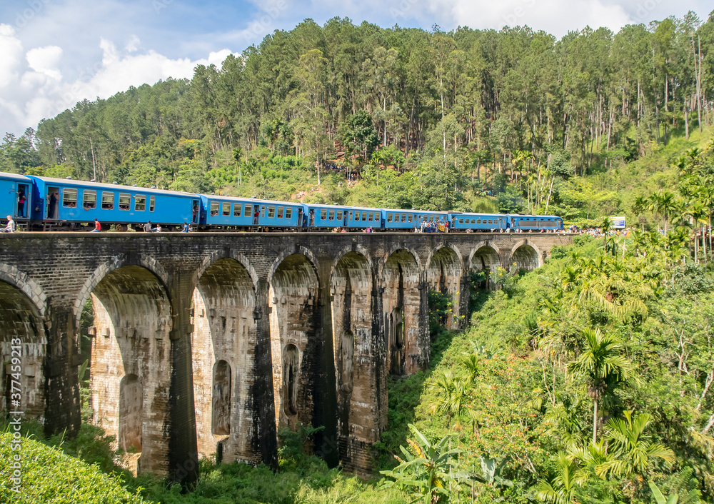 Blue train on the famous Nine Arch Bridge in the jungle on the island of Sri Lanka