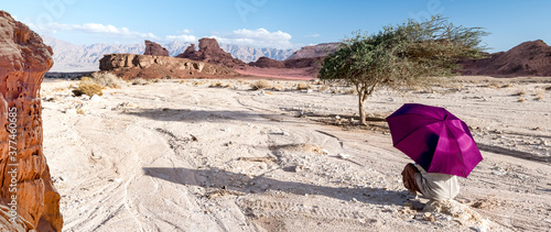Hiker with umbrella among stone desert and mountains, Middle East