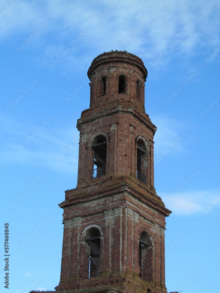 Tower of an old abandoned Church against a blue sky with clouds