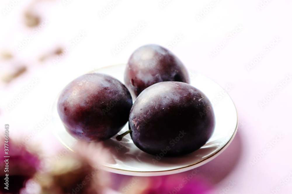 Fresh plums on a white saucer close-up, bokeh - the concept of using vitamin berries in cooking Fresh plums on a white saucer close-up, bokeh - the concept of using vitamin berries in cooking