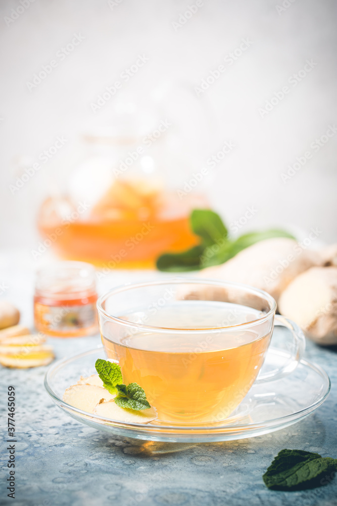 Ginger tea in a glass cup with lemon and mint on light background Ginger tea in a glass cup with lemon and mint on light background