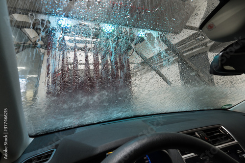 Automatic car wash with conveyor belt. A view from the car through the windshield at the rotating brushes, water and shampoo photo