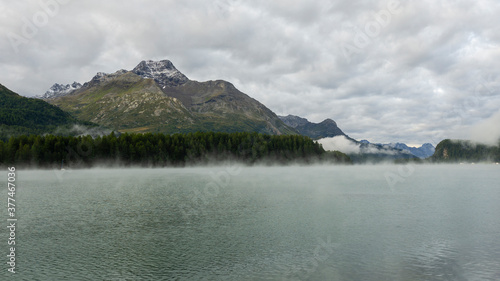 Maloja mountain Pass, Switzerland. Landscape of the lake Sils in the morning during the fall time. The fog covers the lake and the shores. Traditional Swiss contest. Natural landscape