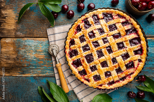 Delicious homemade classic cherry pie with a flaky crust on blue rustic background, top view