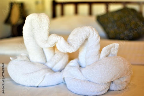 White towel swans are placed on a bed to welcome new guests to a hotel room