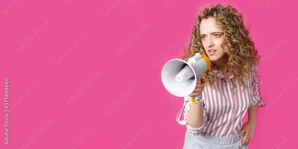 Young woman speaks into a megaphone. Isolated pink background. Young woman speaks into a megaphone. Isolated pink background.