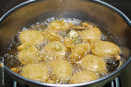 FRYING INDIAN SUBCONTINENT FOOD NAMED PAKORA (ALOO BHAJIYA) IN OIL