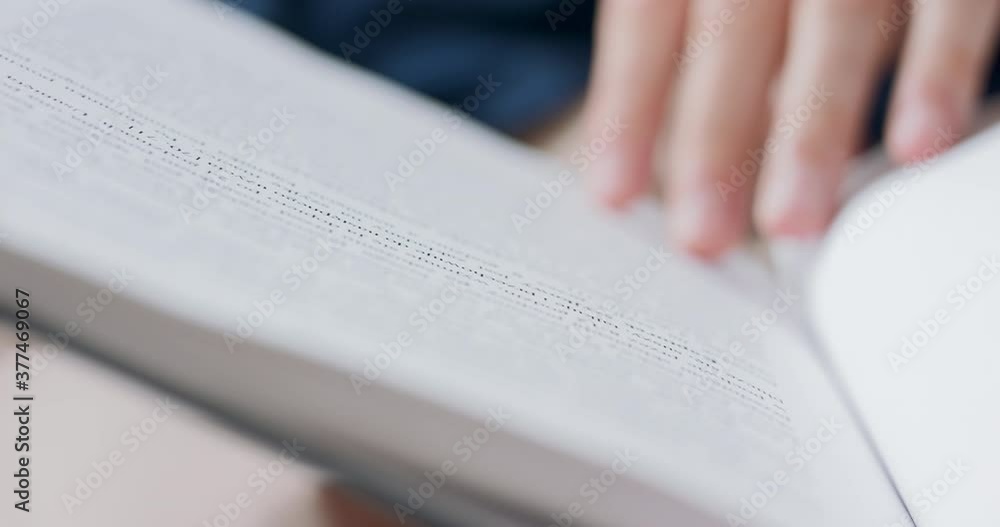 Closeup view of a book pages with some lines of focused text in it. Male hands holding a book are blurred. Closeup view of a book pages with some lines of focused text in it. Male hands holding a book are blurred.