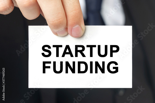 Businessman shows a card with the text - STARTUP FUNDING