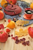 autumn tea party.Thanksgiving Day. teapot, a cup of tea, apples,pumpkin, chestnuts and autumn leaves on a light wooden table.Autumn cozy mood.Fall season