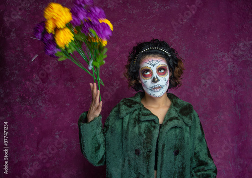 Mujer joven millennial bonita maquillaje catrina mexicana latina día de los muertos halloween calavera cara pintada festividad disfraces fondo rosa punk moderna urbana modelo expresión lanzando flores