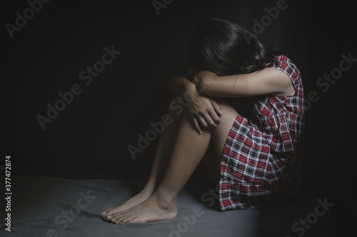 Lonely scared young girl sitting in bed room, Children abuse