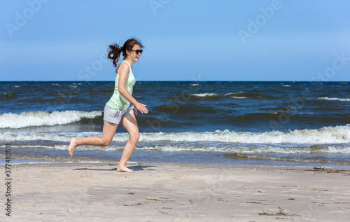 Teenage girl running  jumping on beach 