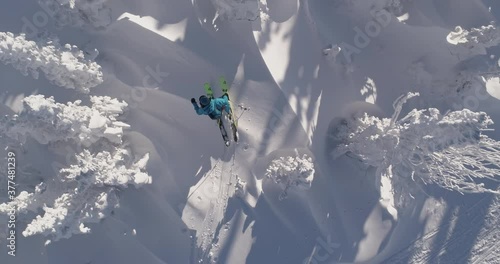 AAerial: Ski touring man crossing over the camera view. Ski touring in the mountains in winter season fresh snow. guy of ski touring on skin uphill in a line. Powder day. ski vacation travel concept