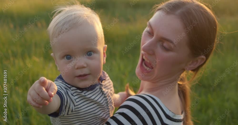 Cute infant points a finger at the camera on hands on mother's hands Cute infant points a finger at the camera on hands on mother's hands