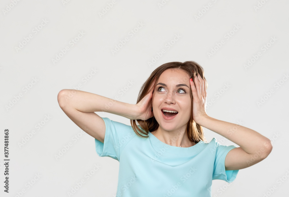 Surprised woman. Special offer. Portrait of excited overwhelmed lady in blue looking at empty space smiling touching head isolated on light. Commercial background. Sale discount. Surprised woman. Special offer. Portrait of excited overwhelmed lady in blue looking at empty space smiling touching head isolated on light. Commercial background. Sale discount.