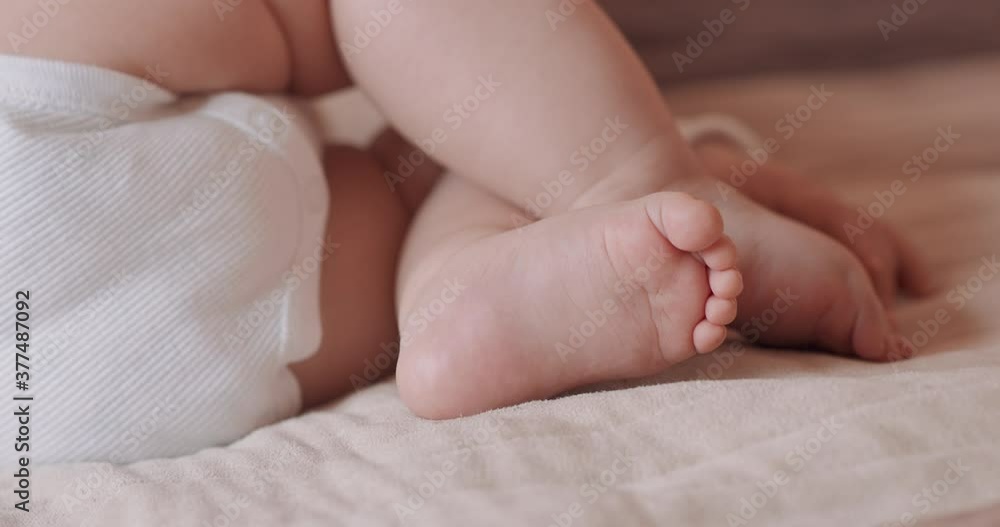 Close up feet of a beautiful sleeping baby, naked, in diapers, on the bed. Close up feet of a beautiful sleeping baby, naked, in diapers, on the bed.