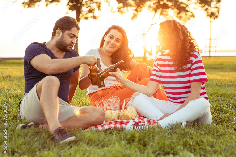 Three friends sitting on the grass in the park