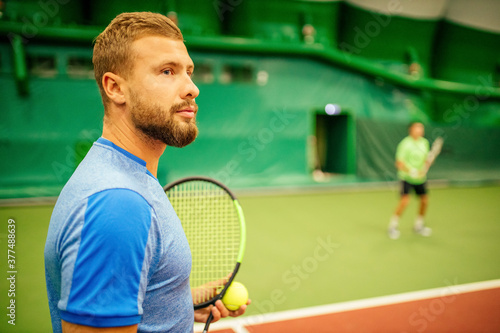 Instructor or coach teaching how to play tennis on a court indoor © yurakrasil