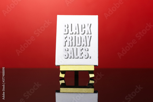 Close-up of black friday sales text, on the small easel. Background of red color.