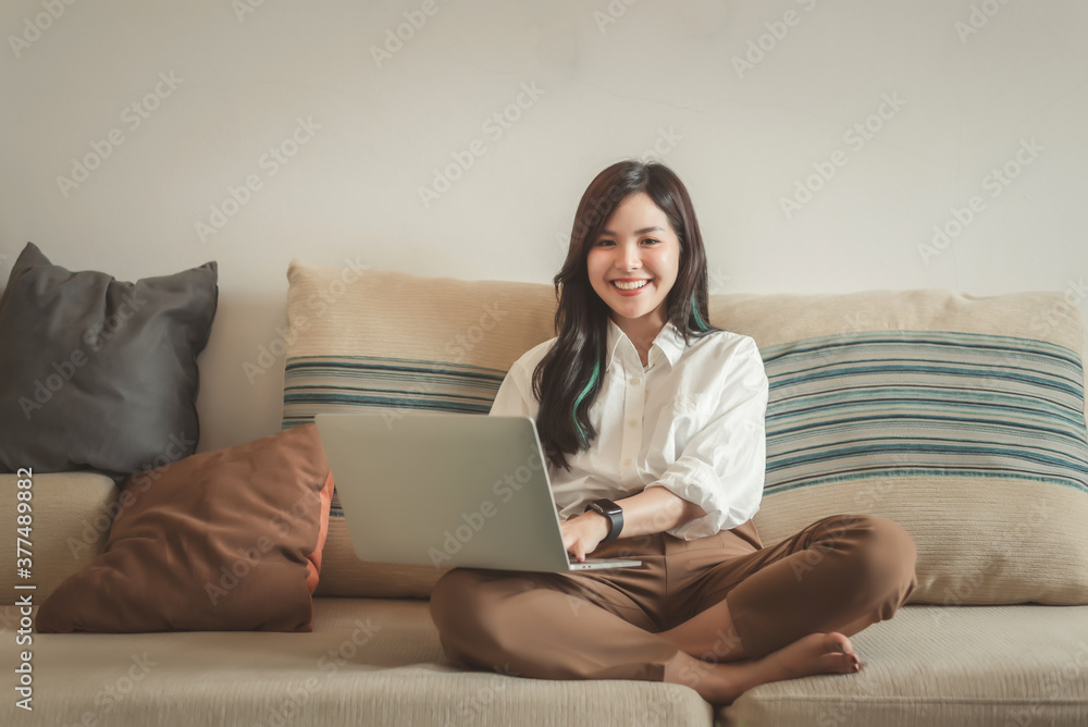 Young pretty asian woman relaxing on sofa at home with laptop computer. Young pretty asian woman relaxing on sofa at home with laptop computer.