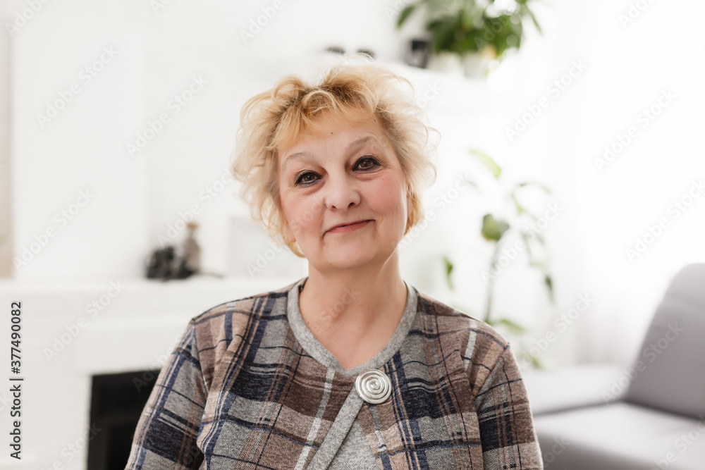 Smiling middle aged mature grey haired woman looking at camera, happy old lady posing at home indoor, positive single senior retired female sitting on sofa in living room headshot portrait Smiling middle aged mature grey haired woman looking at camera, happy old lady posing at home indoor, positive single senior retired female sitting on sofa in living room headshot portrait
