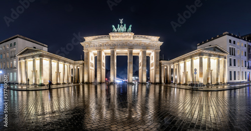 Panorama des beleuchteten Brandenburger Tor in Berlin, Deutschland, bei Nacht und regen mit Reflektionen in der nassen Straße