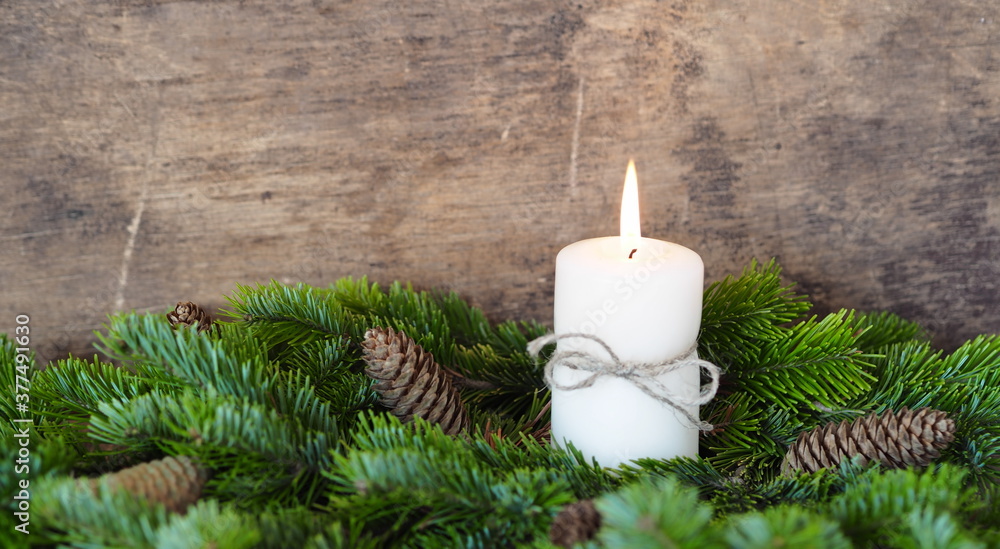 Postcard. Spruce branches are laid out around a lit New Year's candle. Christmas still life. Place for your text.