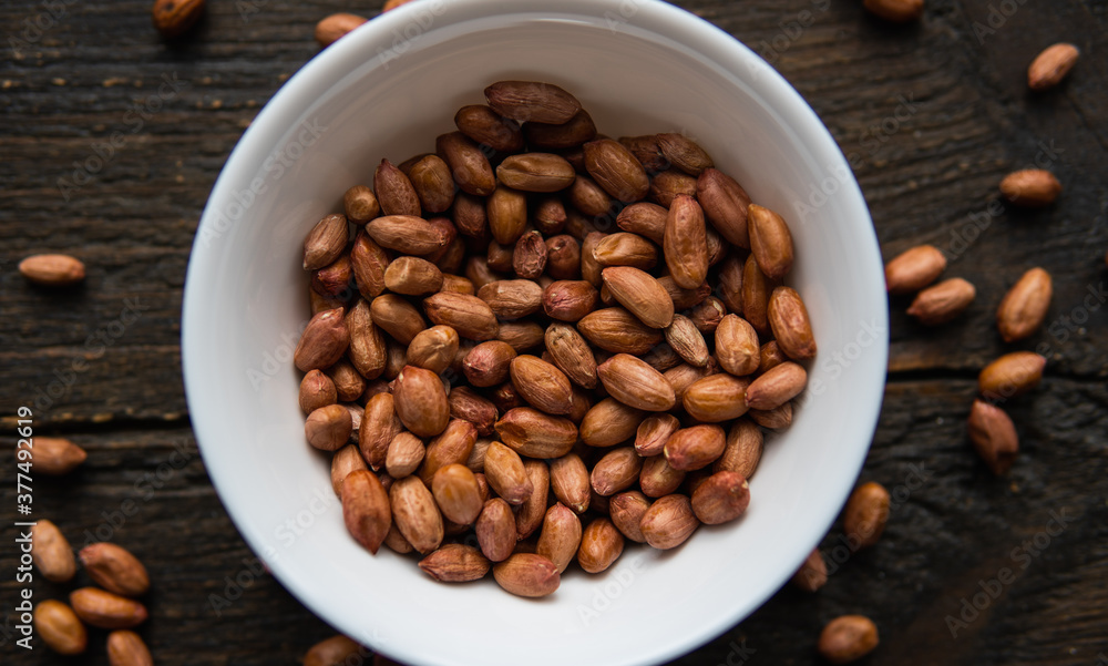 Peanut nuts in a small plate on a vintage wooden table. Peanuts nut is a healthy vegetarian protein nutritious food.