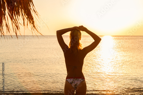 Beautiful blond woman watching alone sunset on the beach. Self-isolation in the open air 