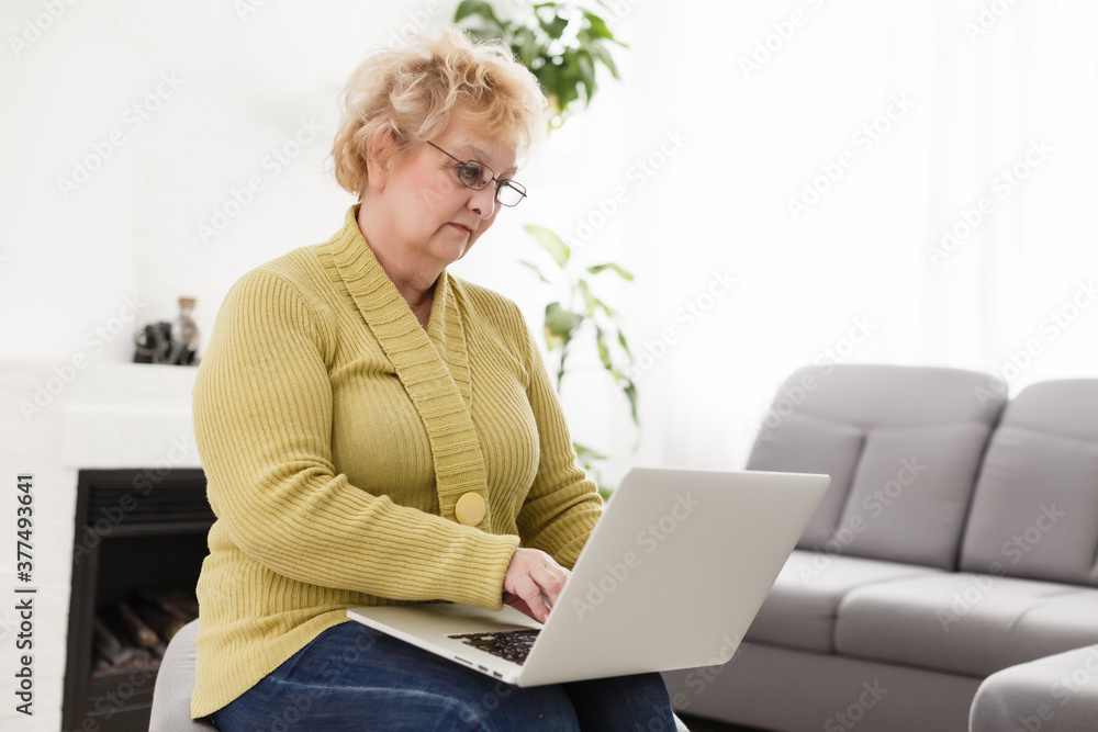 Old woman working on laptop computer at home, Grandma using notebook and searching on internet site Old woman working on laptop computer at home, Grandma using notebook and searching on internet site