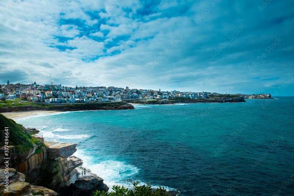 Rock cliffs over the ocean at Bronte Beach with views of the houses at Bondi Beach Sydney NSW Australia Rock cliffs over the ocean at Bronte Beach with views of the houses at Bondi Beach Sydney NSW Australia