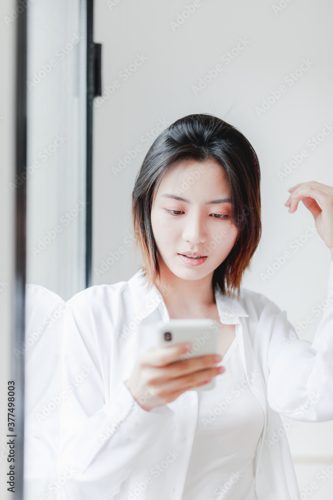 Asian women use mobile phones by French windows Asian women use mobile phones by French windows