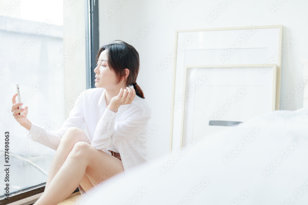 Asian women use mobile phones by French windows Asian women use mobile phones by French windows