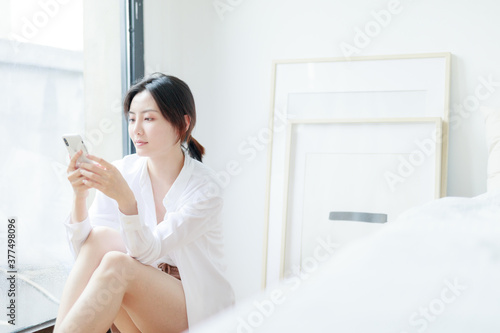 Asian women use mobile phones by French windows